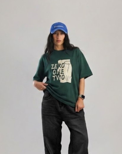 Dark green oversized graphic T-shirt featuring a "ZERO ONE TWO" front print with illustrated artwork and a soft cotton fabric.